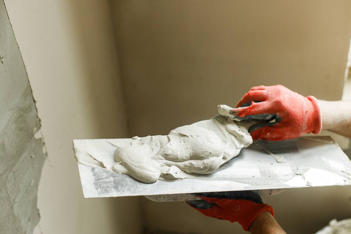 Handyman plastering walls with gypsum plaster and trowel. Construction of house and home renovation concept. Close up of worker hands with spatula and stucco