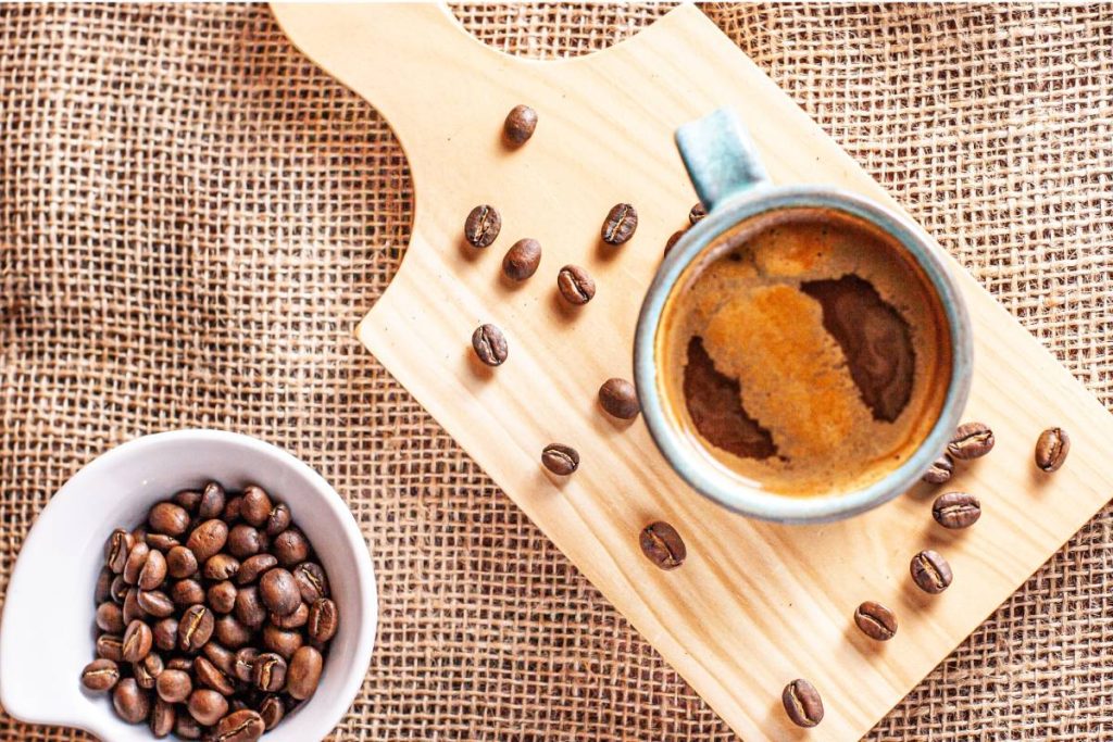 A vertical top view of decaf Americano and coffee beans on a wooden board