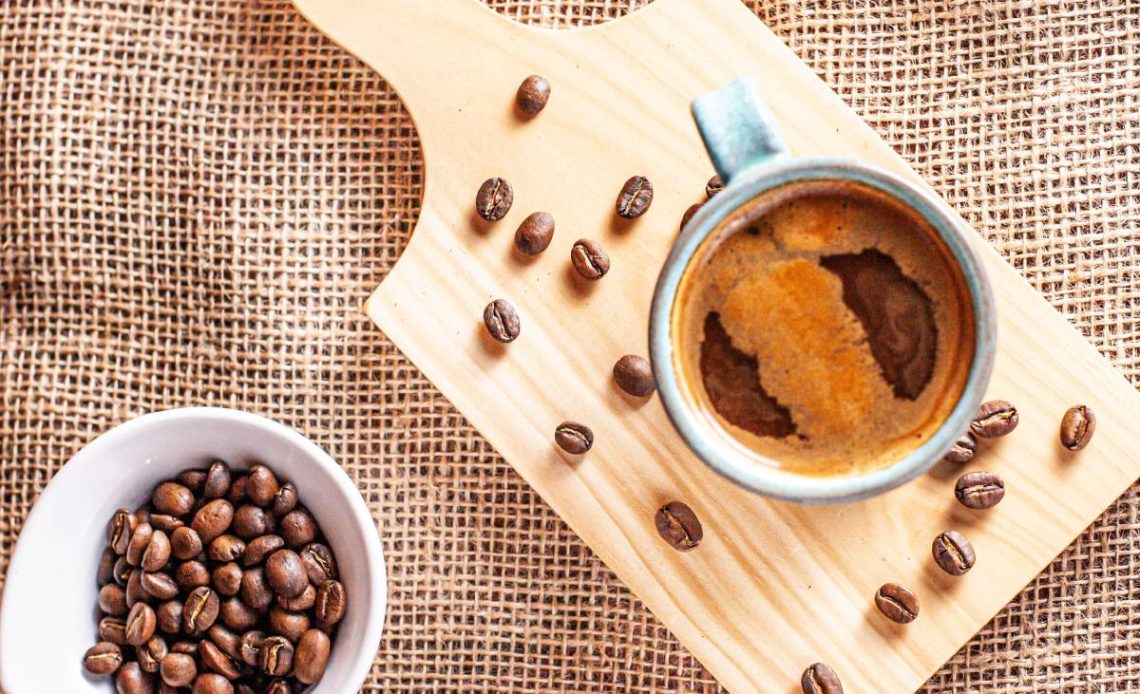 A vertical top view of decaf Americano and coffee beans on a wooden board